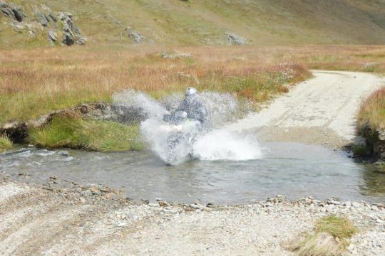 A KLR rider gest enthusiatic on a river crossing.